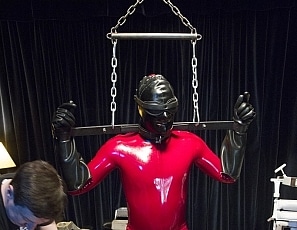 A126_MALEBONDAGE_Stages_SethMichaelPunMyOdes_MetalGearInRedRubberCatsuitFrontRoom