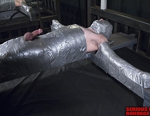 R637_MALEBONDAGE_DuctTapeGod_BobMichael_SilverDuctTapeCrossOverBed