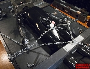 R662_MALEBONDAGE-Chain101_Wired4Fun_BootedRay_Mark_InRubberOnBondageTableWithHeadBoxFrontRoom
