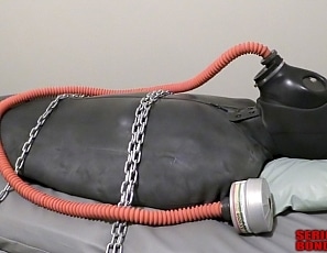 R822_MALEBONDAGE_FunAtBindsPlaceInHamptonIowa_JimmyBindSidBruce_ChainedToJailWall_RubberSleepsack